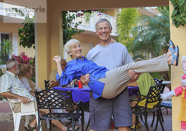 Ein lebenslustiges älteres Paar  der Mann hält die Frau und lächelt in die Kamera