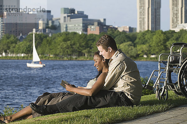 Seitenprofil eines Paares im mittleren Erwachsenenalter  das in einem Park sitzt und ein Buch liest.