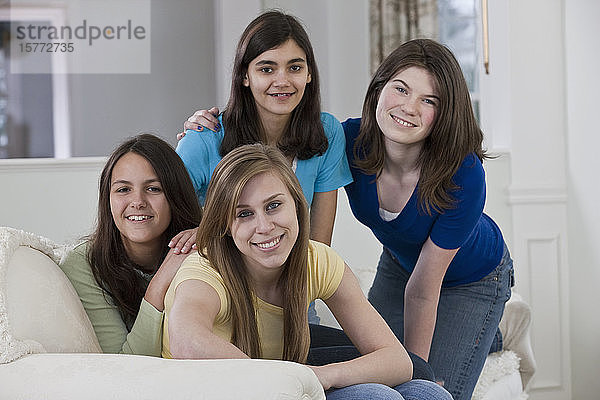 Porträt von vier Mädchen im Teenageralter  die zu Hause auf einer Couch sitzen