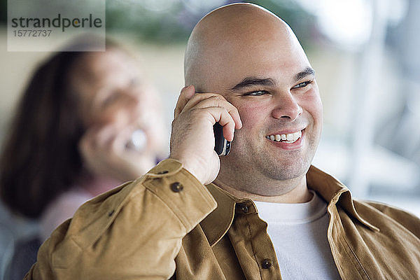 Ein mittelgroßer erwachsener Mann  der sich über ein Mobiltelefon unterhält.