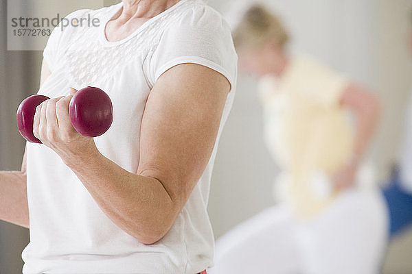 Mittelschnittansicht einer älteren Frau  die mit einem Handgewicht trainiert