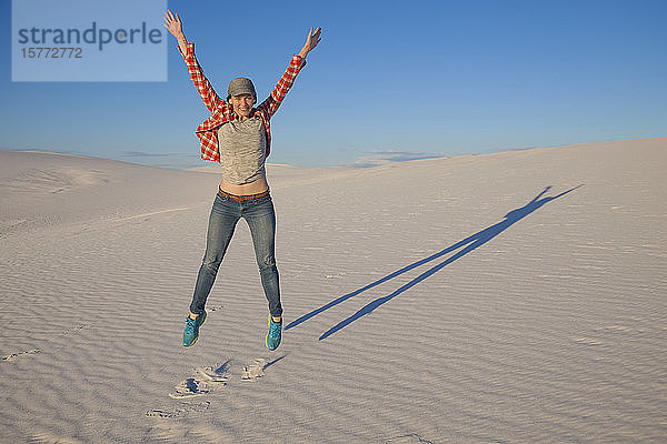 Unbeschwerte junge Frau auf dem weißen Sand mit blauem Himmel  White Sands National Monument; Alamogordo  New Mexico  Vereinigte Staaten von Amerika