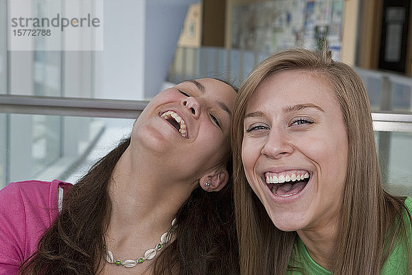 Zwei Teenager-Mädchen lachen zusammen  eine schaut in die Kamera