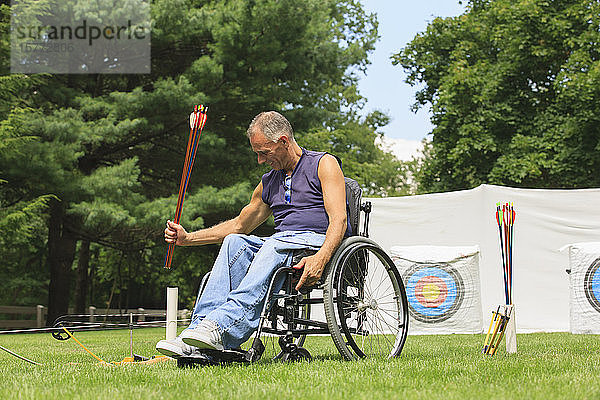 Mann im Rollstuhl auf einem Bogenschießplatz mit Pfeilen