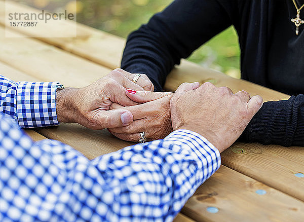 Ein reifes Ehepaar betet gemeinsam an einem Picknicktisch  nachdem es einige Zeit damit verbracht hat  über seinen Glauben zu sprechen; St. Albert  Alberta  Kanada