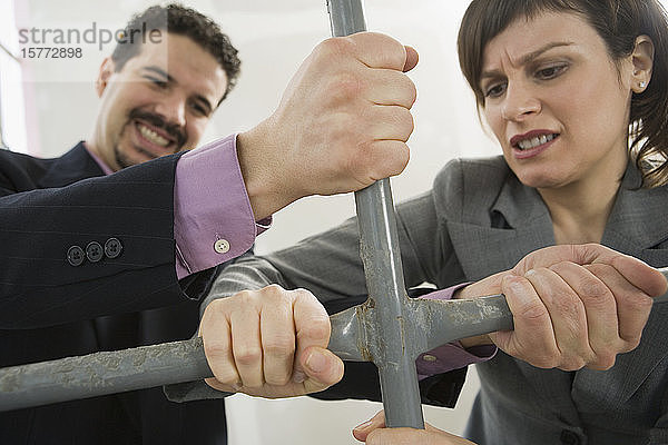 Ein Geschäftsmann und eine Geschäftsfrau halten sich an der Stange eines Gerüsts fest