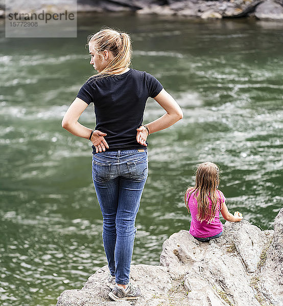Zwei Schwestern verbringen Zeit miteinander am Rande eines Flusses; British Columbia  Kanada