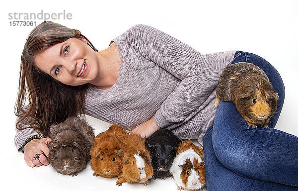 Eine Frau posiert mit ihren Hausmeerschweinchen (Cavia porcellus) vor einem weißen Hintergrund; Studio