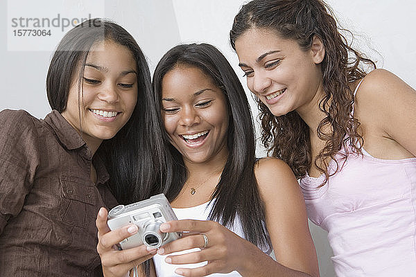 Drei Mädchen im Teenageralter schauen in eine Digitalkamera und lächeln