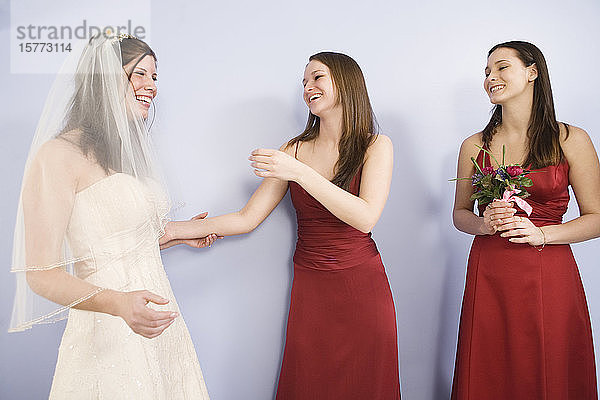 Fröhliche junge Braut mit Brautjungfern stehend.
