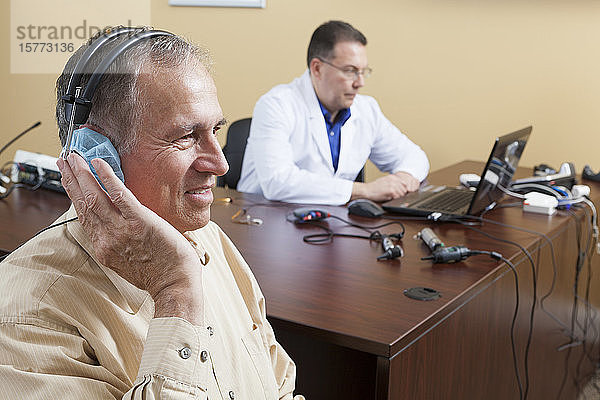 Audiologin führt einen Hörtest bei einem älteren Mann durch