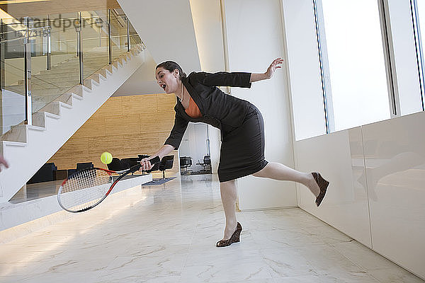 Geschäftsfrau beim Tennisspielen in einem Büro.