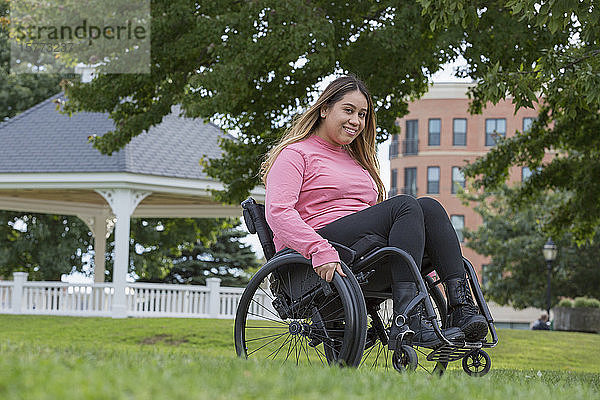 Frau mit Rückenmarksverletzung sitzt im Rollstuhl in einem Park