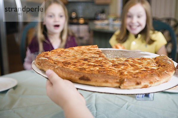 Blick auf zwei Mädchen  die sich eine Pizza ansehen.