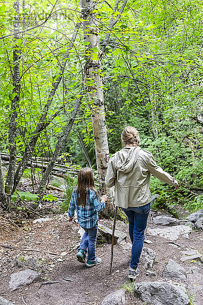 Zwei Schwestern gehen auf einem Waldweg; British Columbia  Kanada
