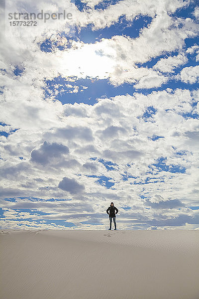 Junge Frau steht auf dem weißen Sand mit blauem Himmel und Wolken  White Sands National Monument; Alamogordo  New Mexico  Vereinigte Staaten von Amerika