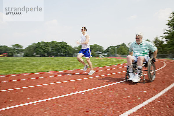 Ein junger Mann fährt ein Rennen mit einem behinderten älteren Mann auf einer Rennbahn.