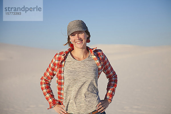Porträt einer jungen Frau  die auf dem weißen Sand mit blauem Himmel steht  White Sands National Monument; Alamogordo  New Mexico  Vereinigte Staaten von Amerika