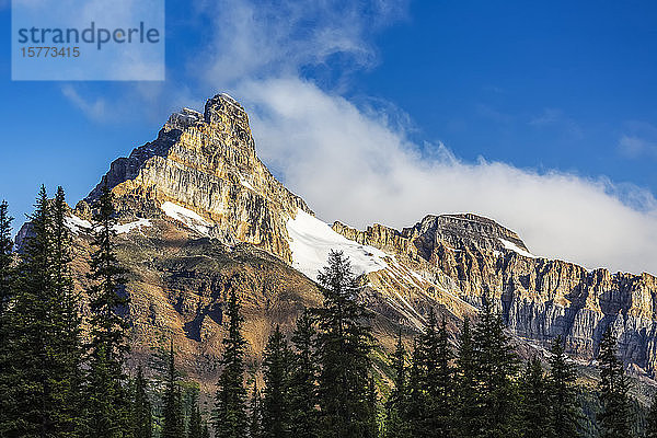 Von der Sonne dramatisch beleuchteter Berggipfel mit blauem Himmel und Wolken  Yoho National Park; Field  British Columbia  Kanada