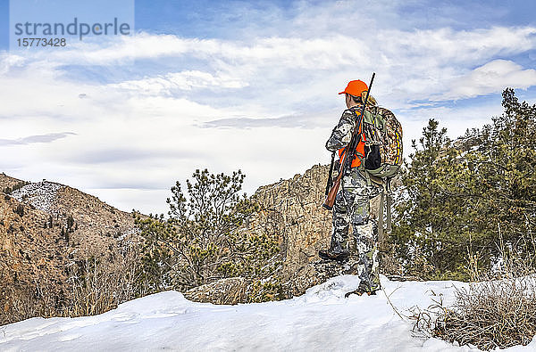 Jäger mit Tarnkleidung und Gewehr  der im Winter nach draußen schaut; Denver  Colorado  Vereinigte Staaten von Amerika