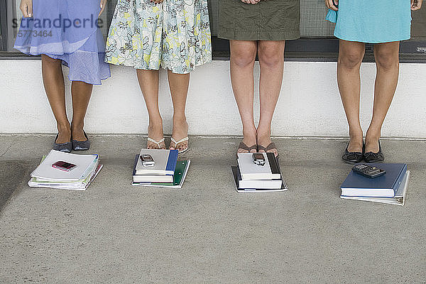Tiefschnittansicht von vier Mädchen im Teenageralter  die in der Nähe von Büchern in einer Schule stehen