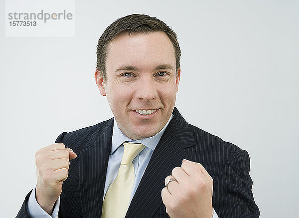 Porträt eines Geschäftsmannes  der seine Fäuste ballt und lächelt