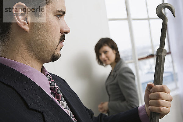 Nahaufnahme eines Geschäftsmannes  der ein Spannschloss hält  mit einer Geschäftsfrau  die ihn im Hintergrund anschaut