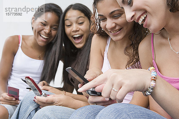 Vier Mädchen im Teenageralter benutzen Mobiltelefone