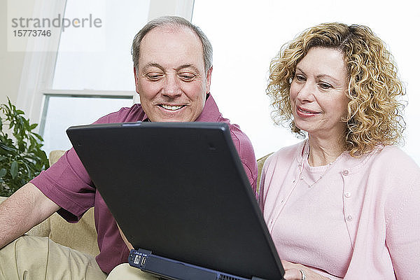Blick auf ein lächelndes Paar  das einen Laptop benutzt.
