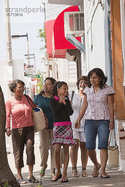 Frauen aus drei Generationen verbringen Zeit miteinander  indem sie einen Bürgersteig entlanggehen