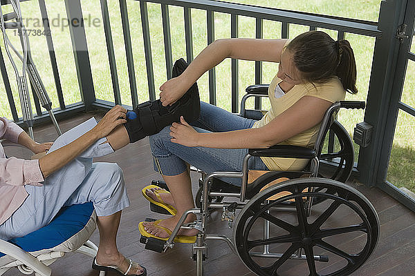Blick von oben auf eine junge Frau  die in einem Rollstuhl sitzt und eine Amputation ihrer Mutter korrigiert