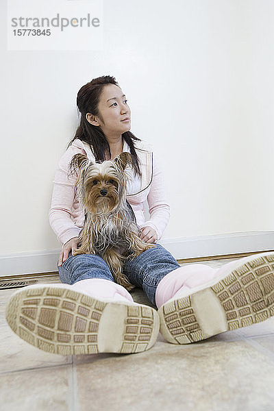 Junge Frau auf dem Boden liegend mit einem Yorkshire Terrier auf dem Schoß