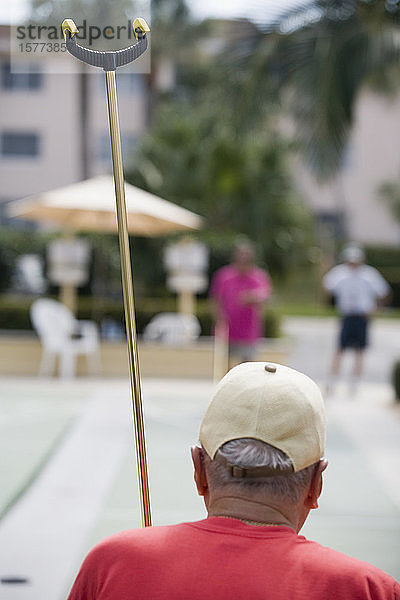 Rückansicht eines älteren Mannes beim Shuffleboard spielen