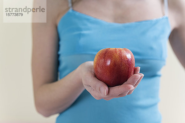 Eine schöne junge Frau  die einen Apfel hält.
