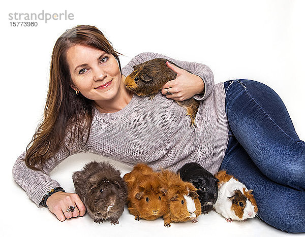 Eine Frau posiert mit ihren Hausmeerschweinchen (Cavia porcellus) vor einem weißen Hintergrund; Studio