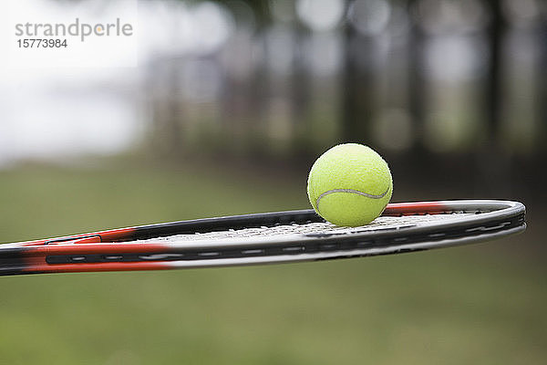 Tennisball auf einem Tennisschläger balanciert