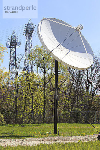Satellitenschüssel mit Stromtransportmasten im Hintergrund