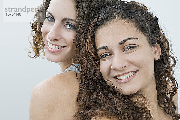 Porträt von zwei lächelnden Teenagern  Rücken an Rücken