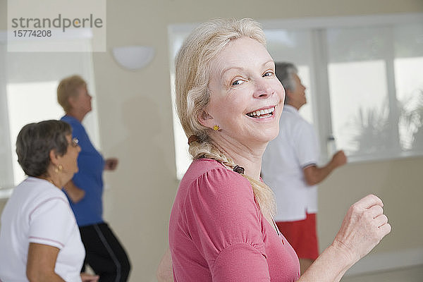 Seitenprofil einer älteren Frau  die in einem Fitnessstudio trainiert und lächelt