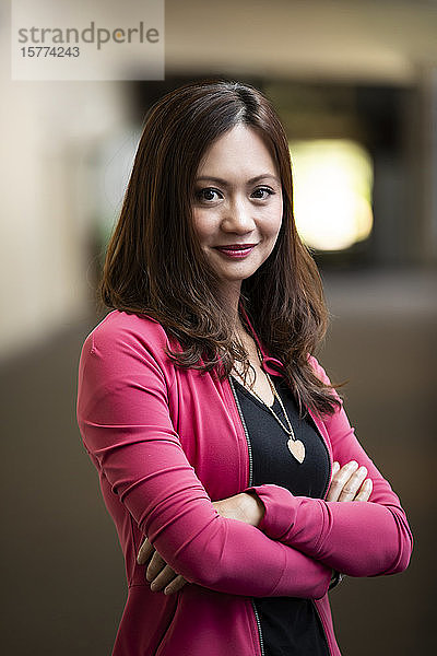 Nahaufnahme eines Porträts einer asiatischen Geschäftsfrau in einem Korridor an ihrem Arbeitsplatz: Edmonton  Alberta  Kanada
