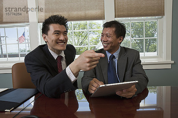 Geschäftsleute sitzen an ihrem Arbeitsplatz und lachen zusammen