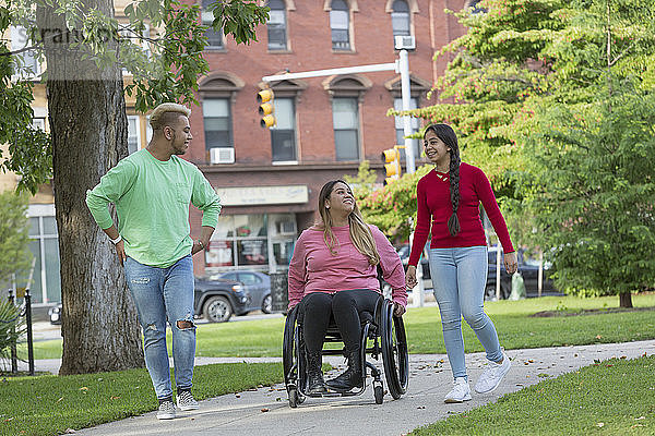 Frau mit Rückenmarksverletzung geht mit Geschwistern im Park spazieren