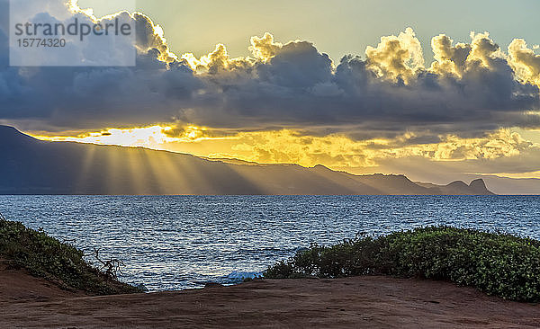 Schönes Sonnenlicht Strahlen Strom durch die Wolken über dem Pazifischen Ozean auf einem abgelegenen Maui  Hawaii Strand. Die Sanddünen und Inseln sind durch den Sonnenuntergang Licht silhouetted; Maui  Hawaii  Vereinigte Staaten von Amerika