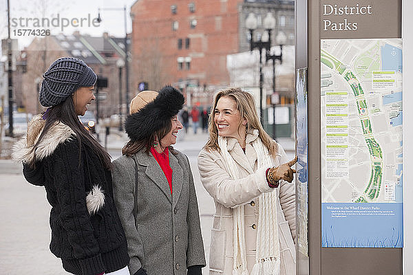 Drei Frauen stehen im Freien und schauen auf einen Stadtplan und eine Werbung; Boston  Massachusetts  Vereinigte Staaten von Amerika