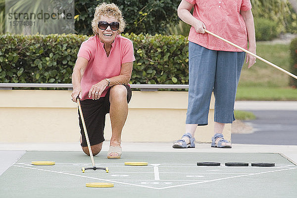 Zwei ältere Frauen spielen Shuffleboard