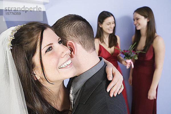 Blick auf eine fröhliche Braut  die ihren Bräutigam umarmt.