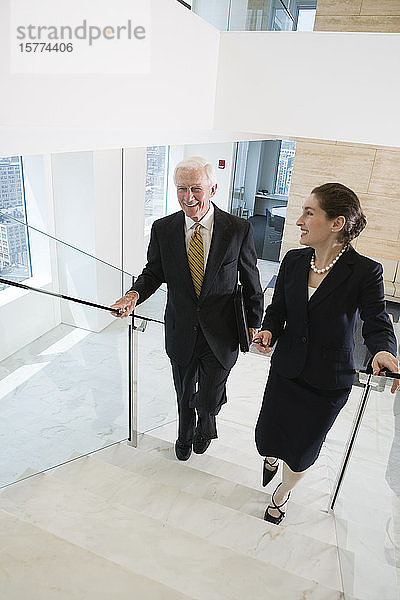 Erhöhte Ansicht von Geschäftsleuten  die auf einer Treppe in einem Büro gehen.