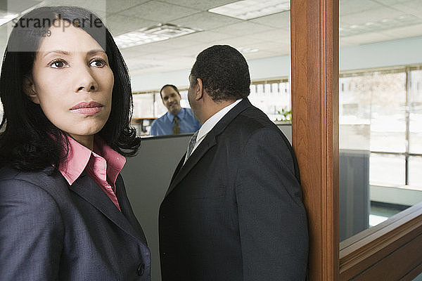 Nahaufnahme einer Geschäftsfrau mit zwei Geschäftsleuten  die in einem Büro stehen