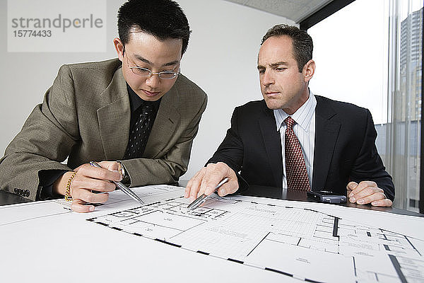 Zwei Architekten diskutieren in einem Büro über Baupläne.