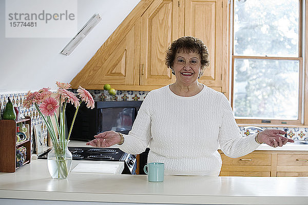 Porträt einer fröhlichen Frau  die in einer Küche steht.